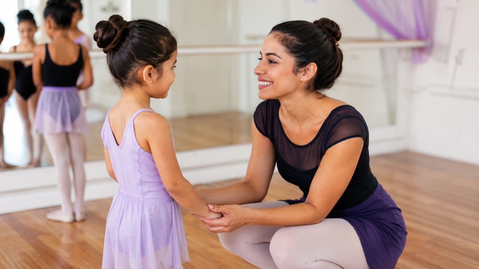 Criança em primeira aula experimental de ballet sendo recebida pela professora numa sala de dança