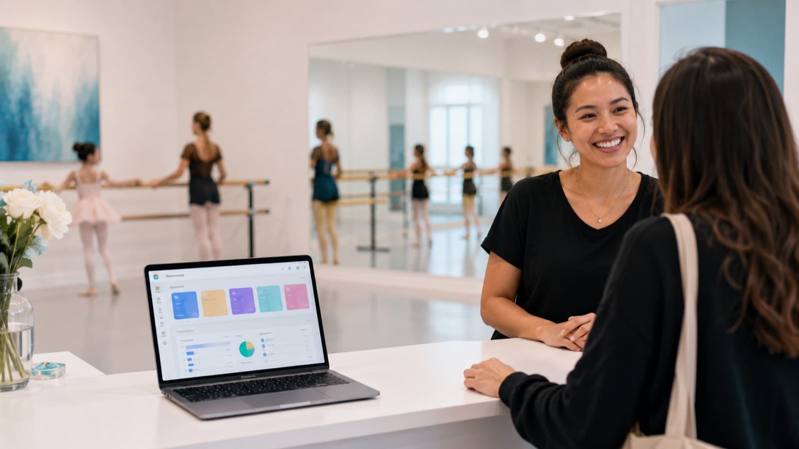 Recepção organizada de escola de dança com computador mostrando painel de gestão de alunos e turmas